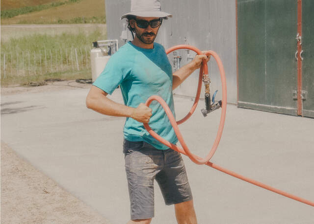 Man wearing Dickies cooling short unraveling a garden hose