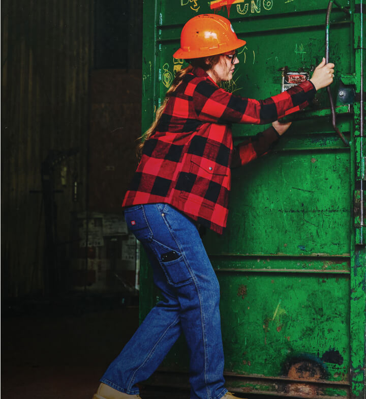 A woman wearing a flannel shirt closing a shipping container.