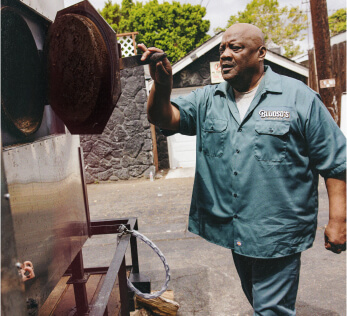 Kevin Bludso checking on the temperature of his barbeque outside.