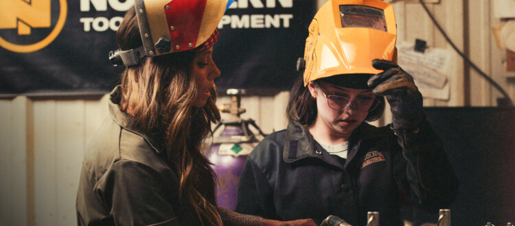 Two females in a workshop looking down.