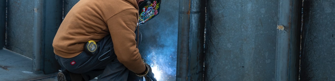 Man kneeling to weld.