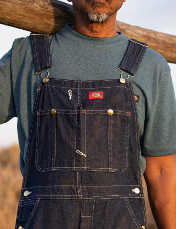 a man wearing dickies bib overalls working outside