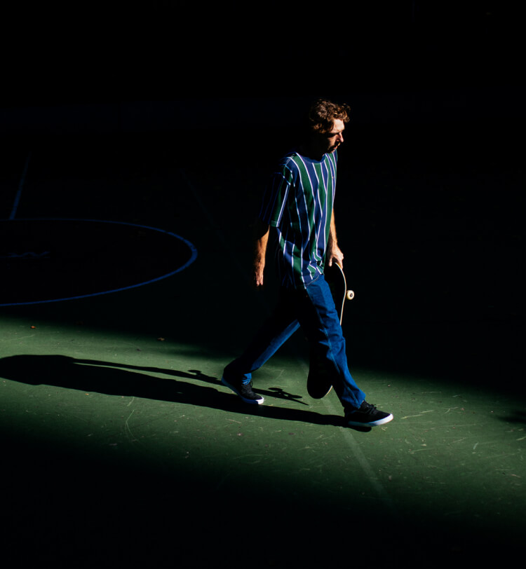 Jake Hayes walking with a skateboard in his hand.