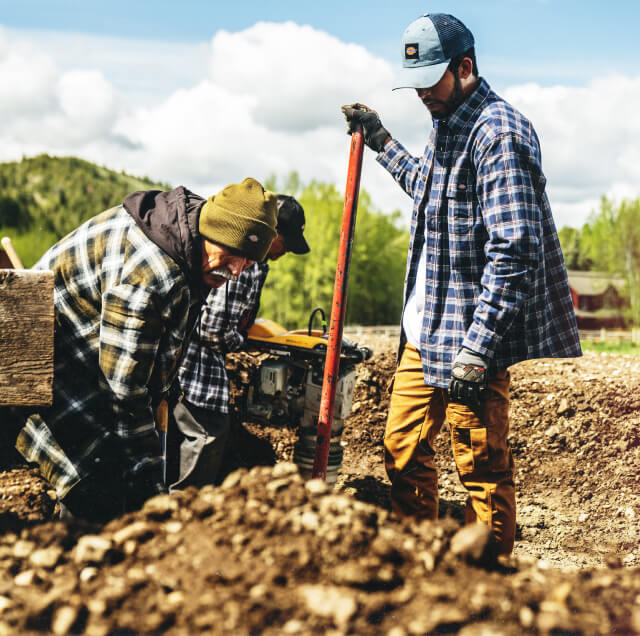 Some workers shoveling out dirt from a hole.