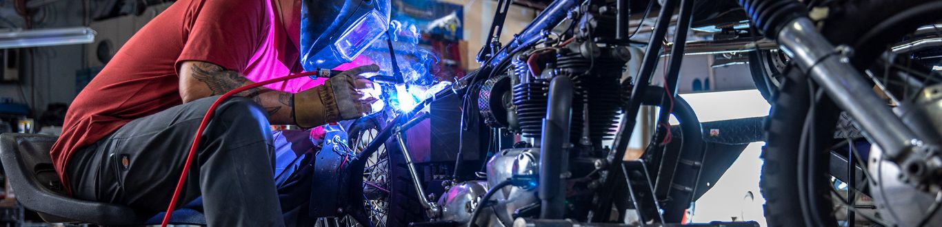 A man using a welding machine on a vehicle.