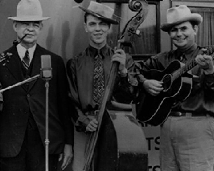 a black and white 1950s photograph of several bluegrass musicians standing in front of a Dickie's van