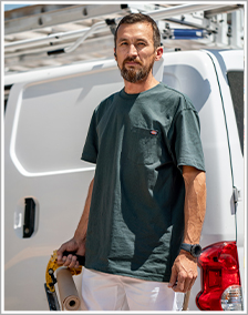 Man wearing a green shirt standing in front of a white work van