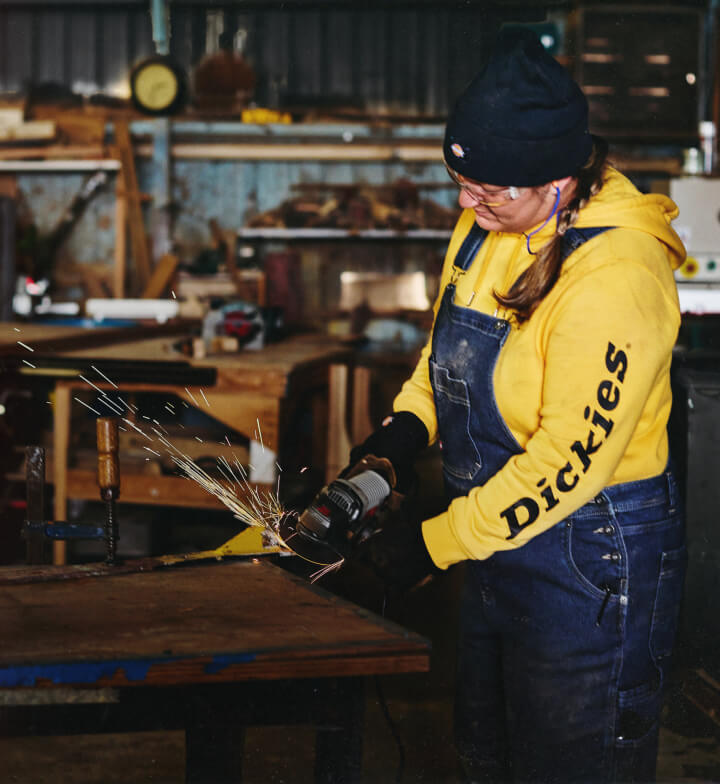 A worker grinding down a piece of metal in a workshop.