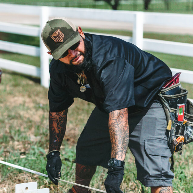 A construction worker bending down to hold a line.