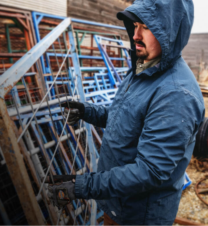 A worker carrying a wire fence wearing a dark blue light jacket.