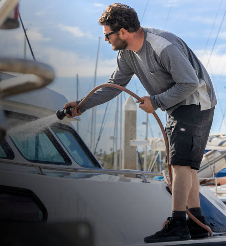 a worker spraying a boat with a water hose