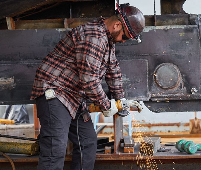 A man grinding down metal in a workplace.
