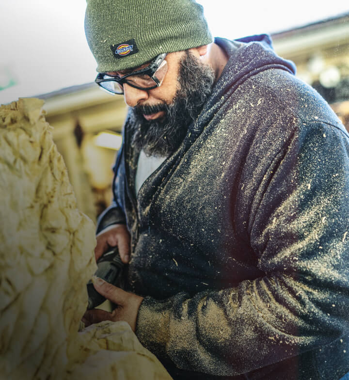 A man wearing a dark dickies hoodie standing in a workshop.